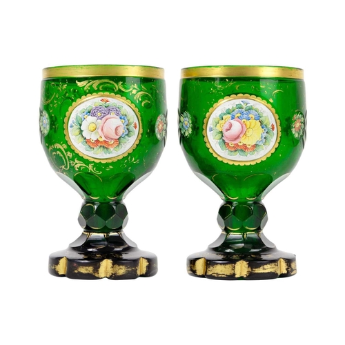 181 - A pair of Bohemian green glass goblets, 19th century. Each with floral painted panels and gilt decor... 