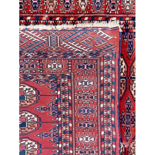 264 - A Tekke rug, circa 1920's. The madder field with two rows of eight large guls, within a sunburst gul... 