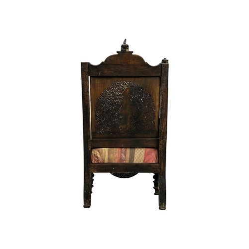 311 - A Burmese carved wood open armchair, 19th century. With two figural finials above a profusely carved... 