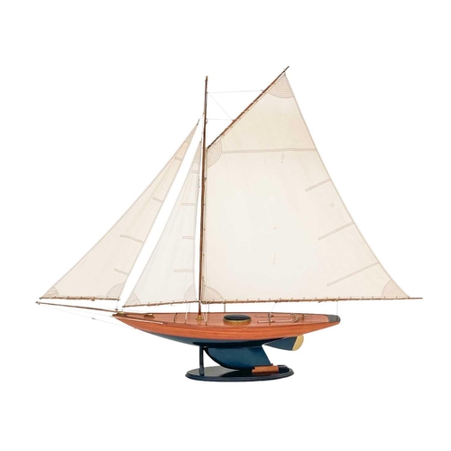 122 - A model of a racing yacht. With a simulated planked deck, painted hull, on a stand, height 123cm.