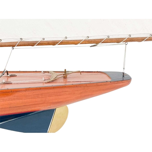 122 - A model of a racing yacht. With a simulated planked deck, painted hull, on a stand, height 123cm.