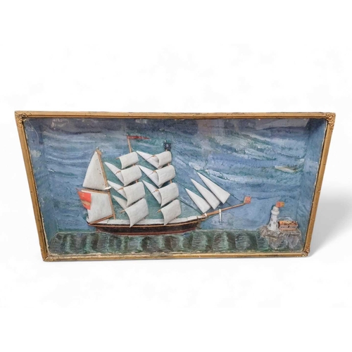 236 - A Victorian diorama of a fully rigged schooner. With a lighthouse, with painted background, and sea,... 