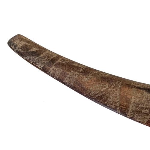 24 - A hardwood boomerang. One face with incised decoration, length 57cm.