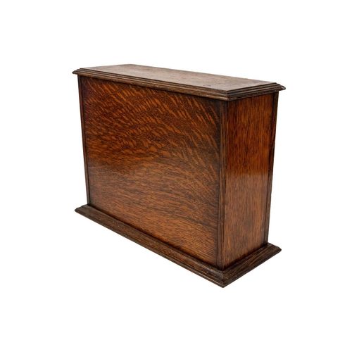 26 - An oak glazed tantalus circa 1900. With bevel glazed fall front door, height 27cm width 36.5cm depth... 