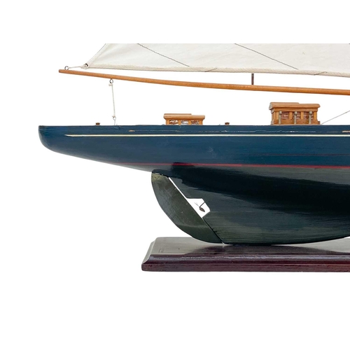 61 - A model of a yacht. Modern, with a blue painted hull, on a painted base, height 110cm.