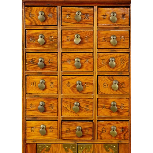 1 - A Chinese hardwood brass bound medicine cabinet, 20th century. With an arrangement of twenty drawers... 