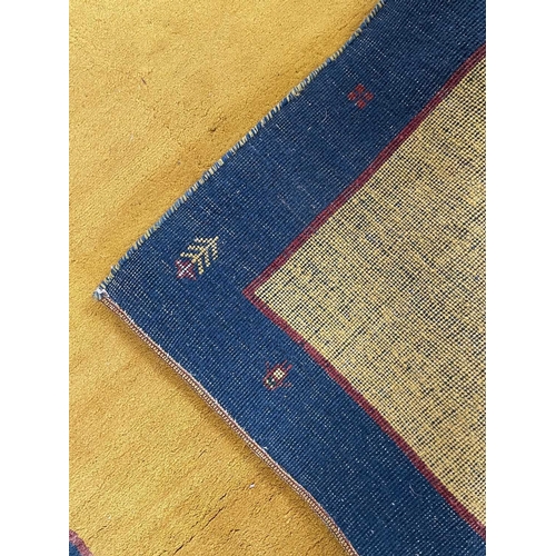 183 - A Gabbeh rug. The rectangular plain yellow field within a blue border with numerous motifs including... 