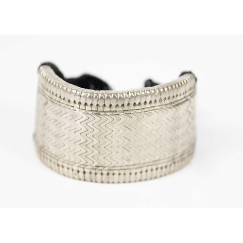 205 - A Persian white-metal belt, early 20th century. Length 69cm and a white-metal bangle. (2)