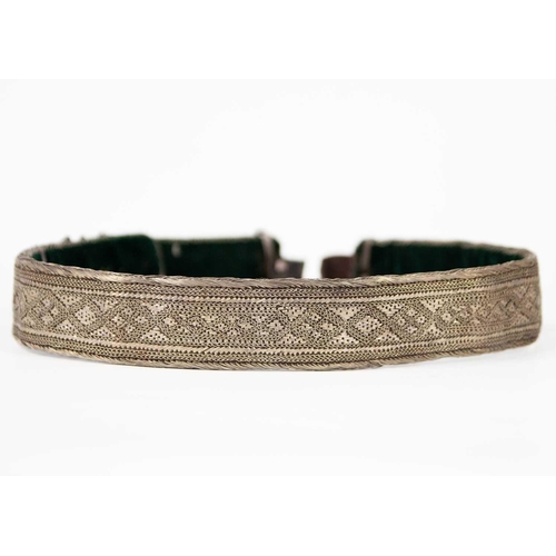 205 - A Persian white-metal belt, early 20th century. Length 69cm and a white-metal bangle. (2)