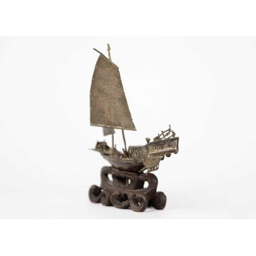 208 - A Chinese silver model of a junk, circa 1900. On a carved wood stand, height 12.5cm, width 11cm, dep... 