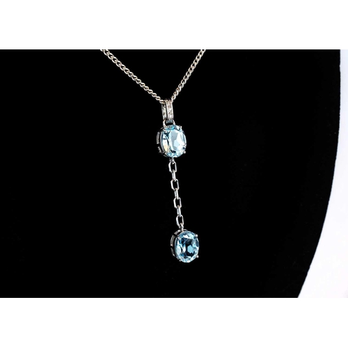 106 - An 18ct white gold blue topaz and diamond set pendant necklace. The pendant set with two topaz each ... 