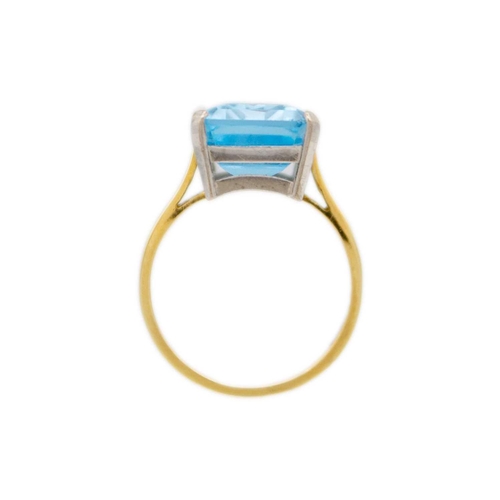 65 - An 18ct yellow and white gold, blue topaz set cocktail ring. The rectangular step cut topaz of 10.6c... 