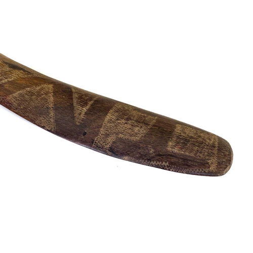 24 - A hardwood boomerang. One face with incised decoration, length 57cm.