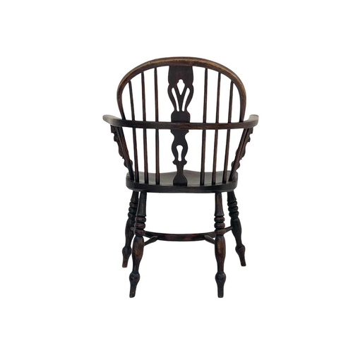 256 - An ash and elm Windsor armchair. With a pierced vase splat, shaped solid seat and a crinoline stretc... 