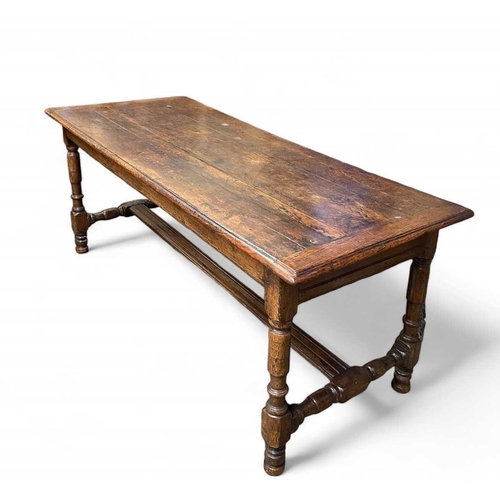 263 - A 17th century oak dining table. With cleated planked top, the turned legs joined with H stretchers ... 