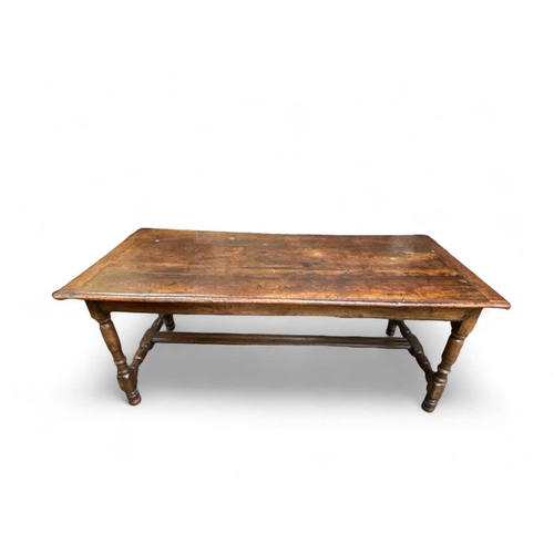 263 - A 17th century oak dining table. With cleated planked top, the turned legs joined with H stretchers ... 