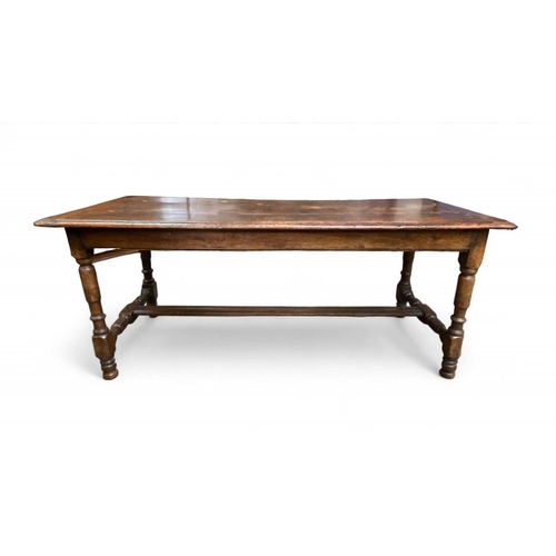 263 - A 17th century oak dining table. With cleated planked top, the turned legs joined with H stretchers ... 