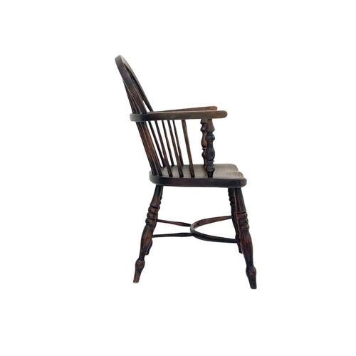 264 - A dark ash and elm Windsor armchair. With a pierced vase splat, solid seat and a crinoline stretcher... 