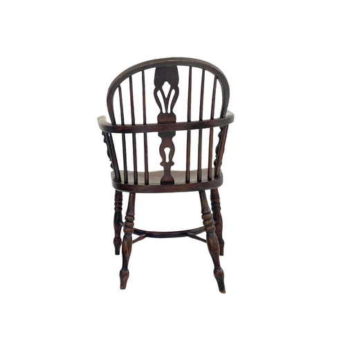 264 - A dark ash and elm Windsor armchair. With a pierced vase splat, solid seat and a crinoline stretcher... 