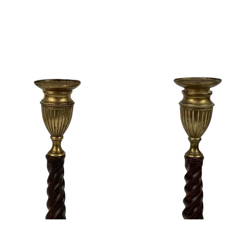 304 - A pair of 19th century mahogany brass mounted candlesticks. With cast urn capital and drip pan, rais... 