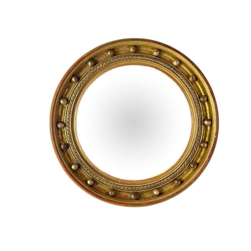 310 - A Regency style circular gilt convex wall mirror. The deeply moulded frame with applied ball ornamen... 