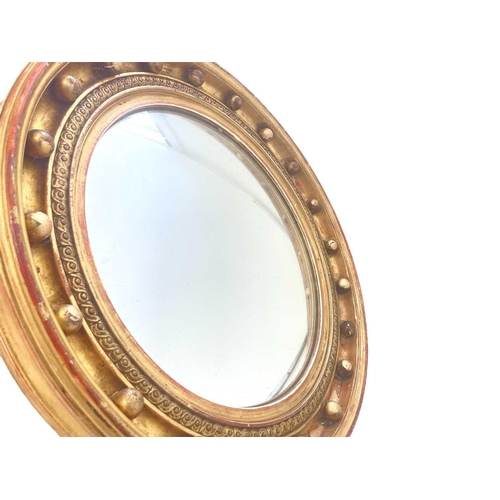 310 - A Regency style circular gilt convex wall mirror. The deeply moulded frame with applied ball ornamen... 