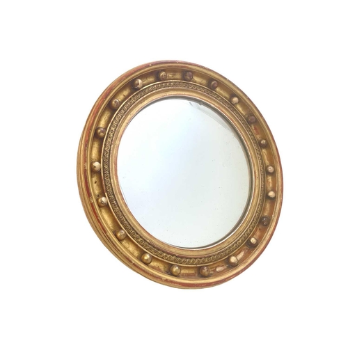 310 - A Regency style circular gilt convex wall mirror. The deeply moulded frame with applied ball ornamen... 