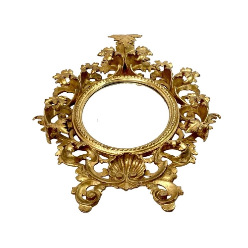 322 - An ornate Florentine oval giltwood rococo style wall mirror. Circa 1900, with typical shell and scro... 