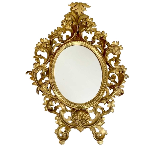 322 - An ornate Florentine oval giltwood rococo style wall mirror. Circa 1900, with typical shell and scro... 