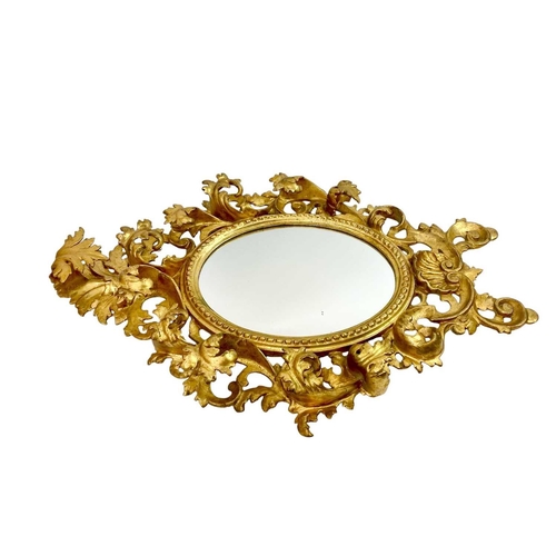 322 - An ornate Florentine oval giltwood rococo style wall mirror. Circa 1900, with typical shell and scro... 