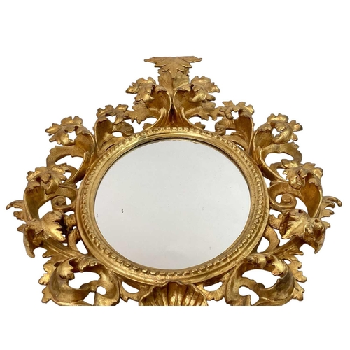 322 - An ornate Florentine oval giltwood rococo style wall mirror. Circa 1900, with typical shell and scro... 