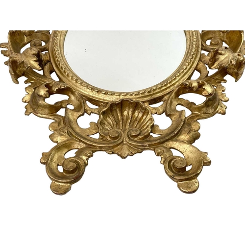 322 - An ornate Florentine oval giltwood rococo style wall mirror. Circa 1900, with typical shell and scro... 