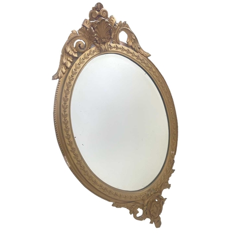 336 - A 19th century gilt gesso oval wall mirror. With shell and scroll cresting, height 96cm, width 57cm.