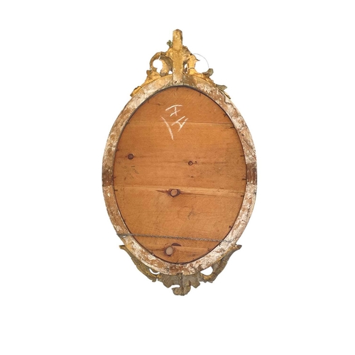 336 - A 19th century gilt gesso oval wall mirror. With shell and scroll cresting, height 96cm, width 57cm.