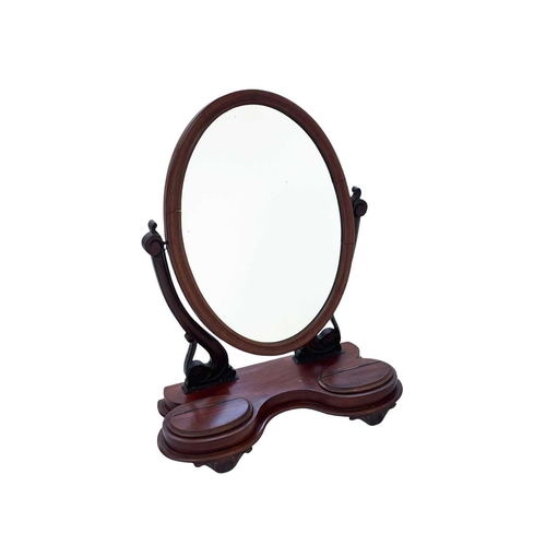 340A - An early 20th century mahogany frame oval toilet mirror. With twin compartments with hinge top lids,... 