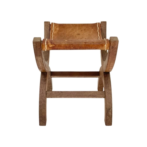 420 - A Robert Thompson 'Mouseman' oak X-frame stool. With a slung leather seat and curved supports, carve... 