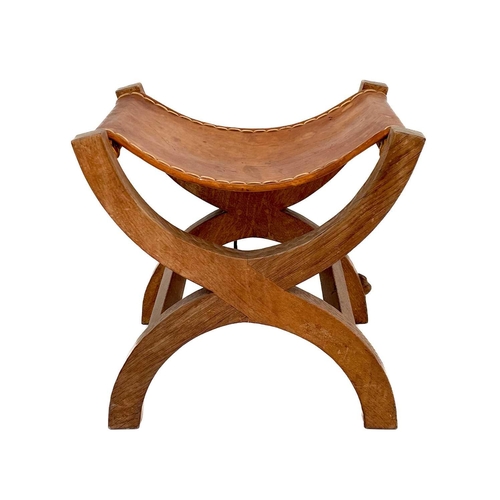 420 - A Robert Thompson 'Mouseman' oak X-frame stool. With a slung leather seat and curved supports, carve... 