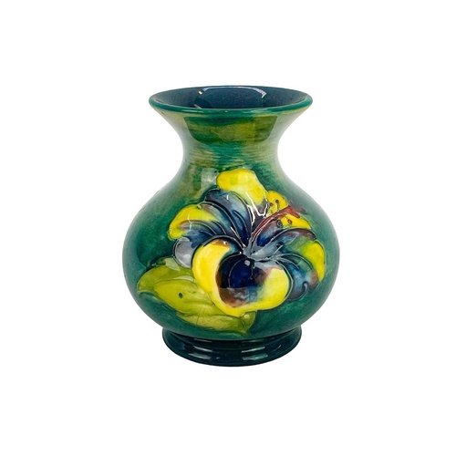 554 - A Walter Moorcroft hibiscus small vase. The flowers painted on a mottled green ground, height 9.5cm,... 