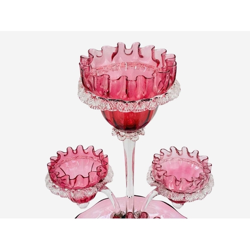 559 - A Victorian cranberry glass epergne. Height 46cm. Flaw at the pontil mark, some bubble inclusions no... 