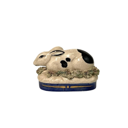 682 - A Staffordshire pottery rabbit. Length 10cm, together with a Staffordshire pottery cat on blue cushi... 