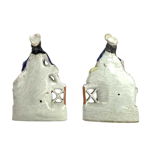 712 - A pair of Victorian Staffordshire flatback figures. Of a boy and a girl seated on a dog kennel, each... 