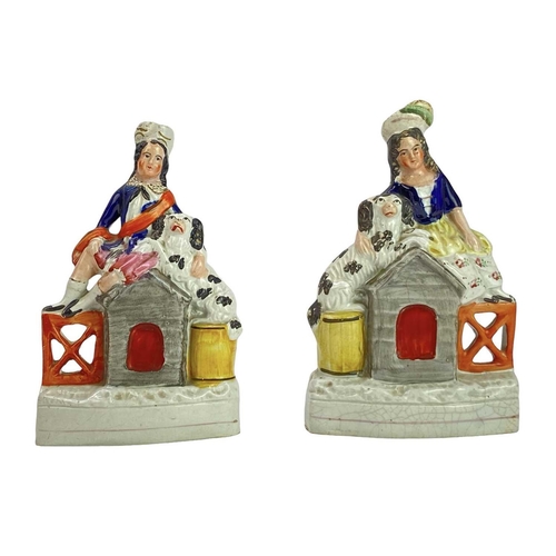 712 - A pair of Victorian Staffordshire flatback figures. Of a boy and a girl seated on a dog kennel, each... 