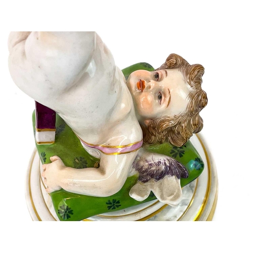 776 - A Meissen figure of Cupid balancing a flaming heart on his foot. Early 20th century, his shoulders r... 