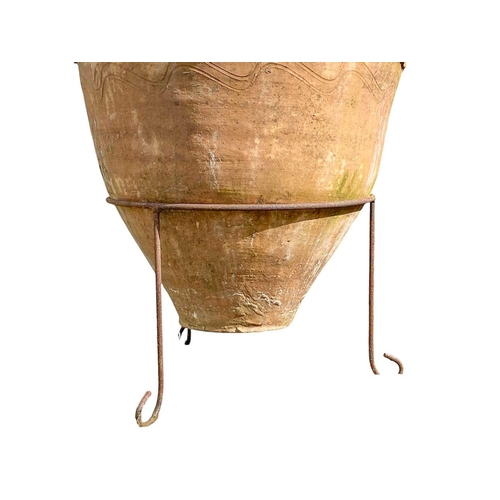 818 - A terracotta storage jar. On wire stand, height 80cm.