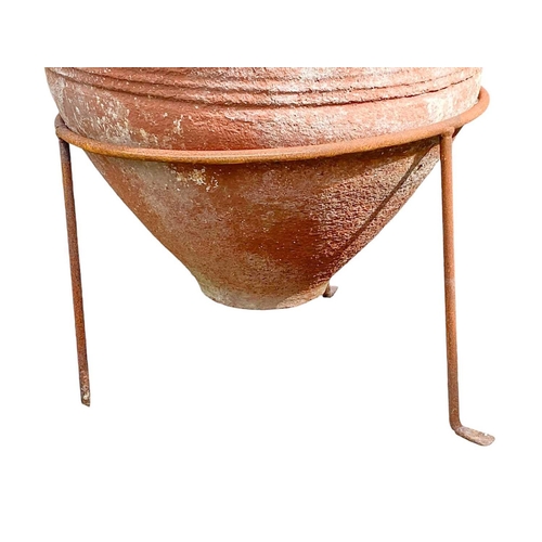 825 - A terracotta storage jar. On wire stand, height 82cm.