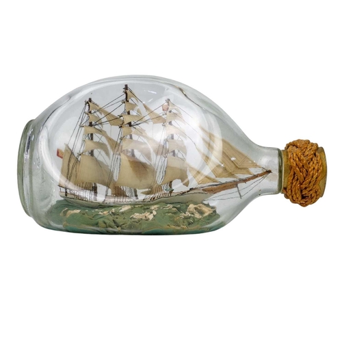 31 - Two bottled ship models A remarkably detailed model ship in a bottle – a three-masted barque with a ... 