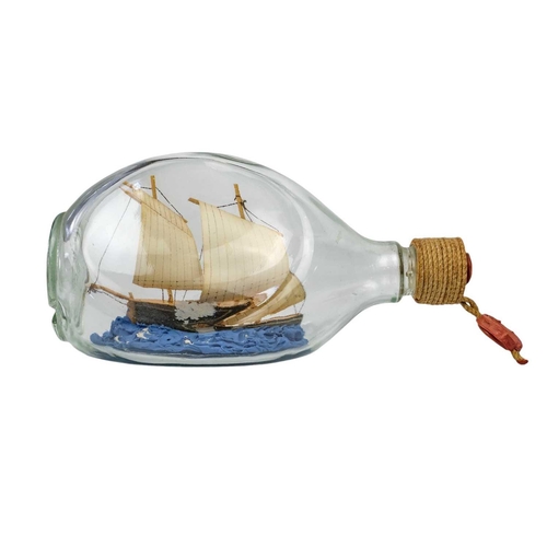 31 - Two bottled ship models A remarkably detailed model ship in a bottle – a three-masted barque with a ... 