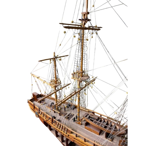 229 - A wooden model of HMS Bounty With detailed rigging, small cannon and upon a stand, open hull to one ... 