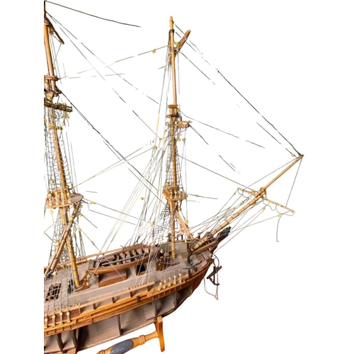 229 - A wooden model of HMS Bounty With detailed rigging, small cannon and upon a stand, open hull to one ... 