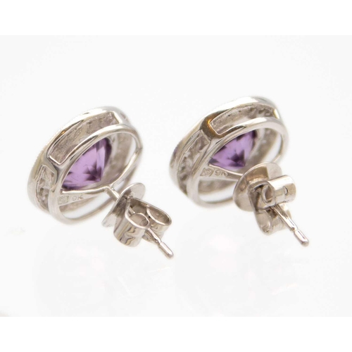 115 - A pair of 9ct white gold amethyst and diamond target earrings. The millegrain set round cut amethyst... 